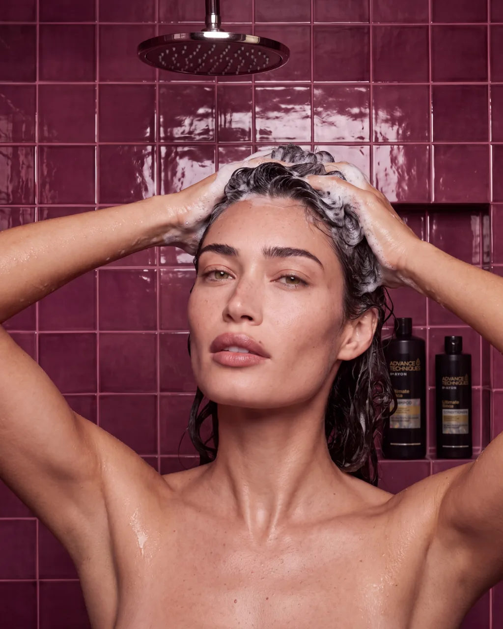 Washing hair in a plum-tiled shower with the products on the shelf