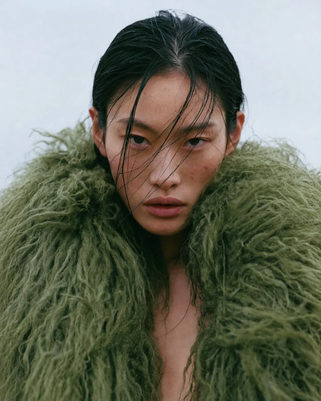 Moss and Salt coastal editorial, model in a green shearling coat against a grey sky