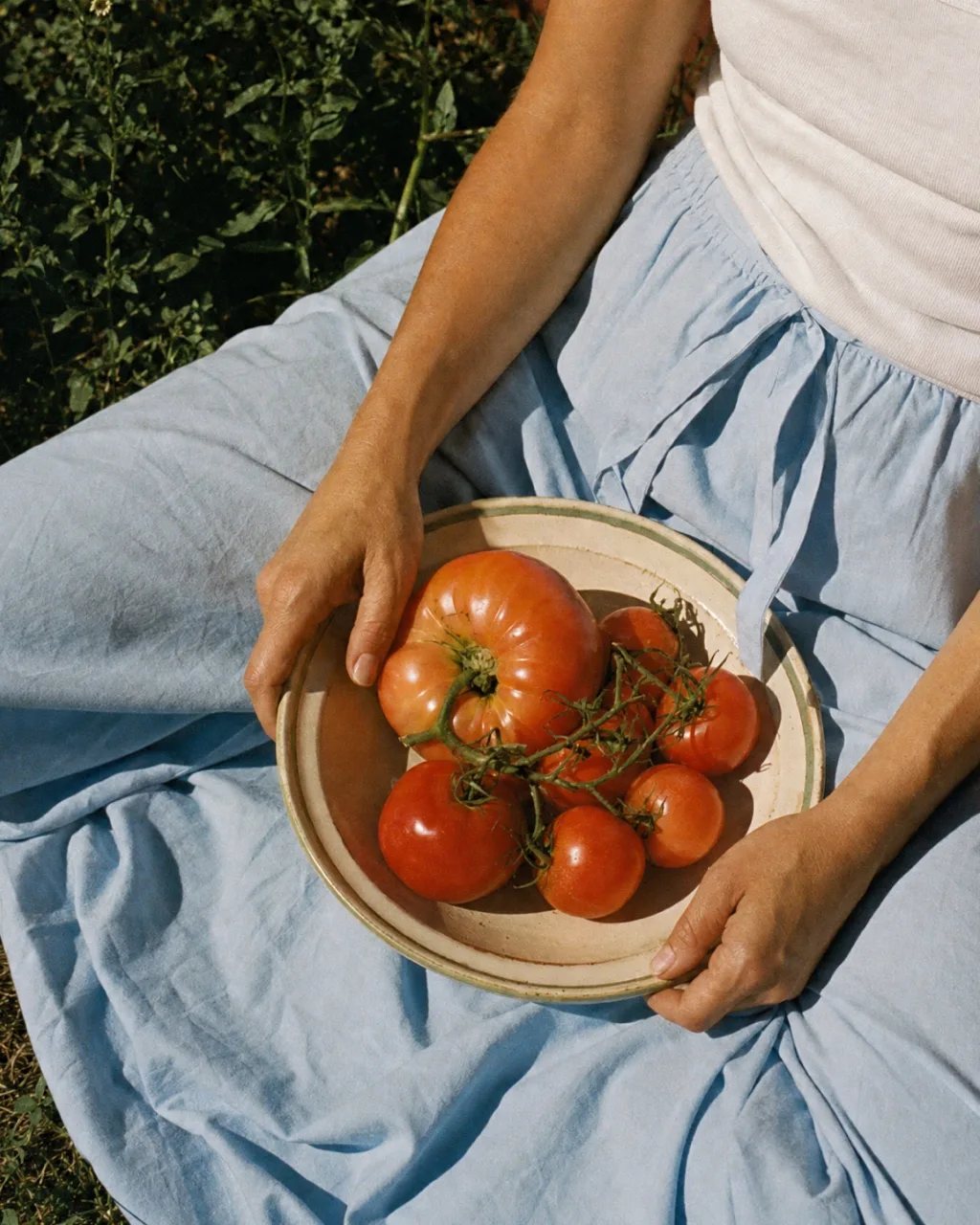 A bowl of tomatoes held over blue linen