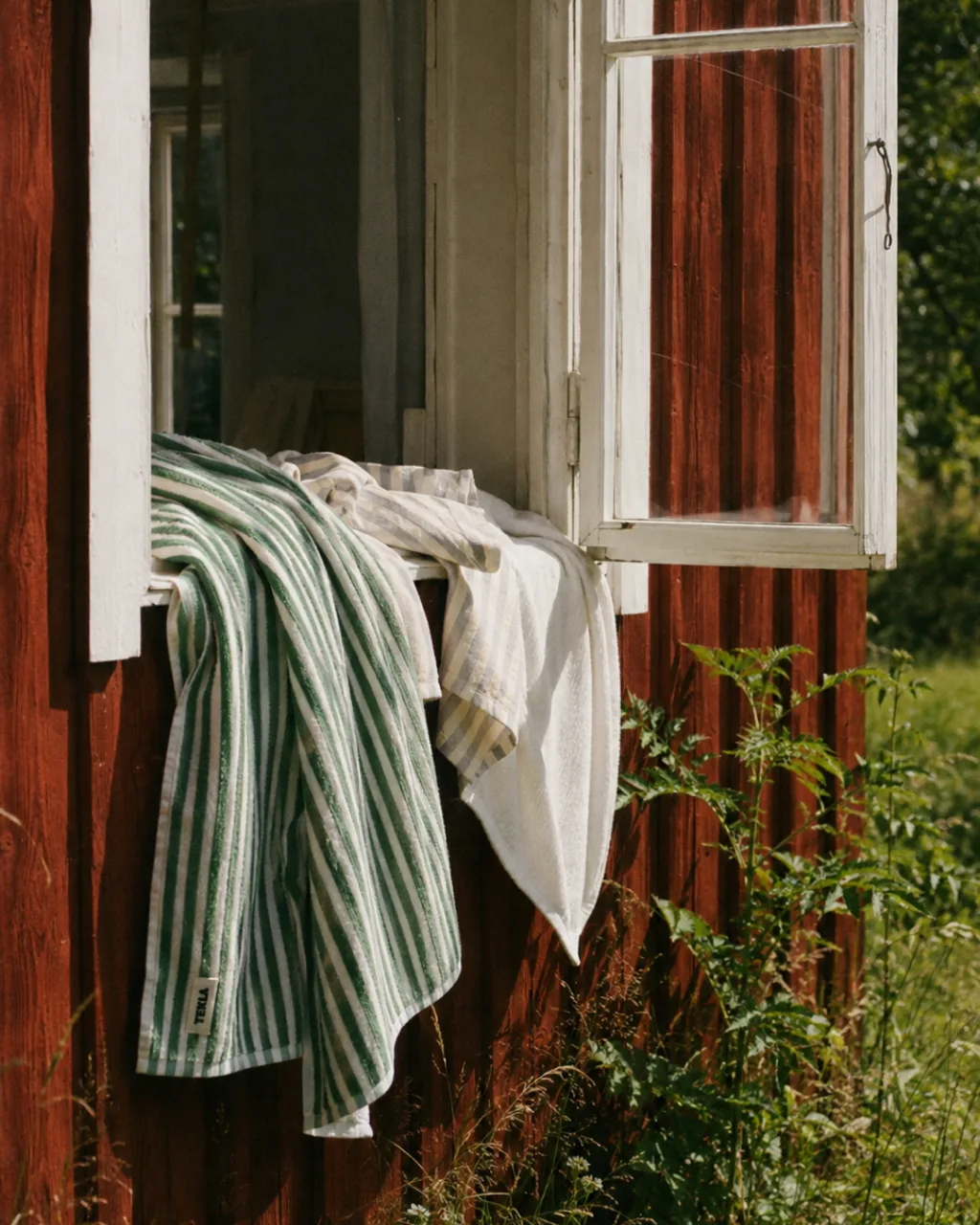 Linen shirt and a green-striped towel hanging over the open window