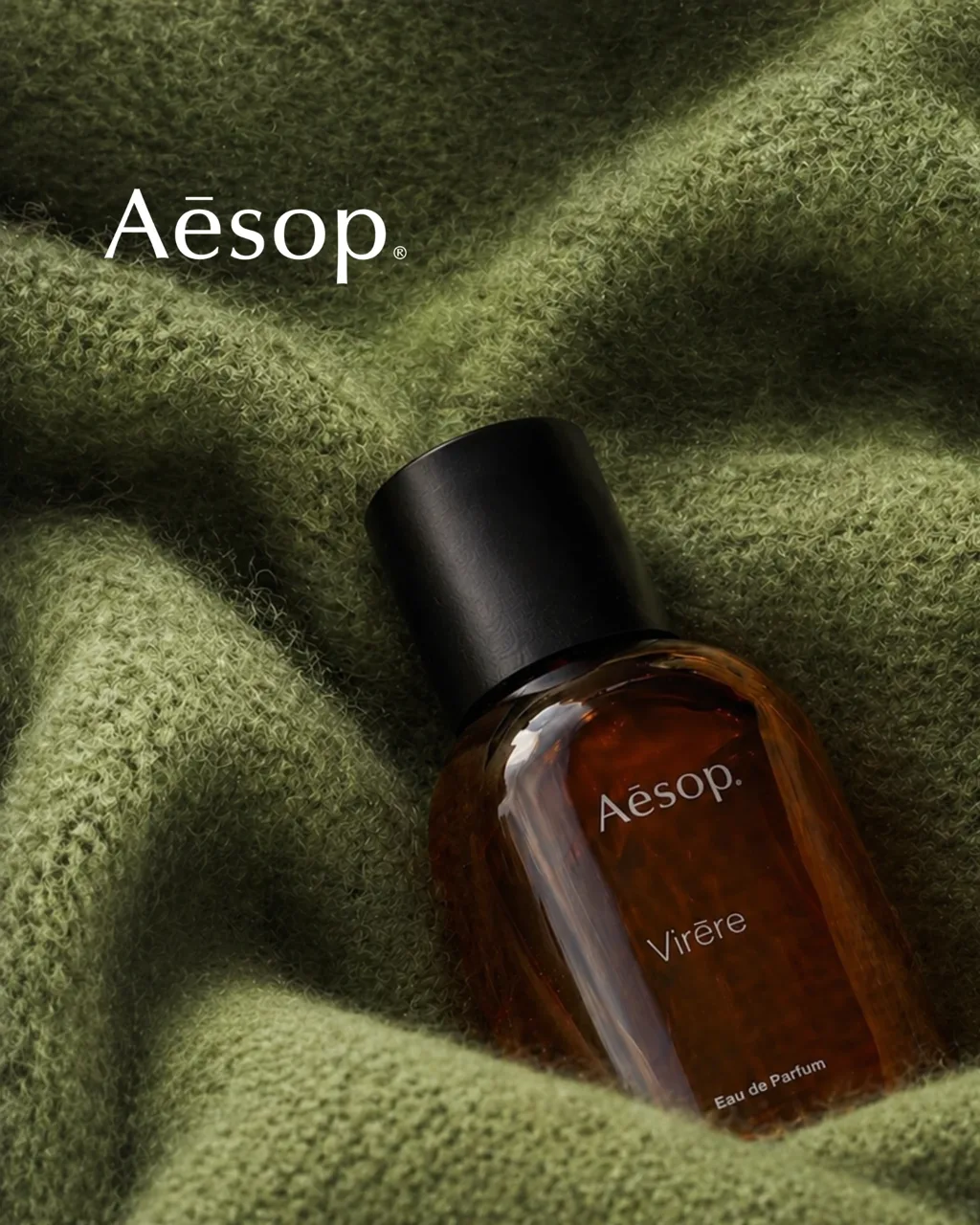Aesop Virēre key visual: the amber eau de parfum bottle on folded green cashmere, with the Aesop wordmark, AI concept work