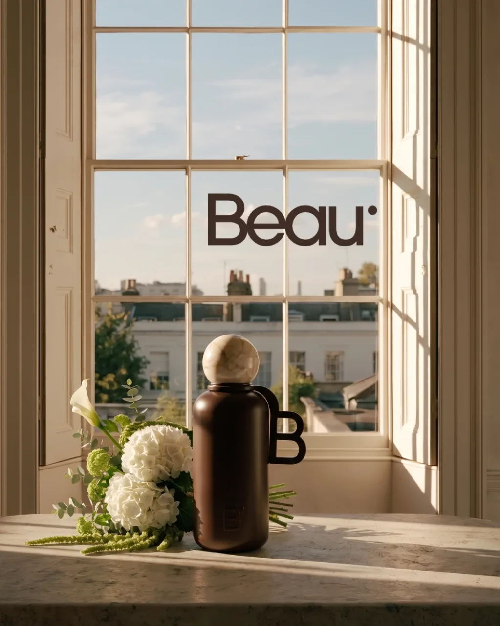 Beau key visual: the insulated bottle and white hydrangeas on a marble table by a window, with the wordmark, AI concept work