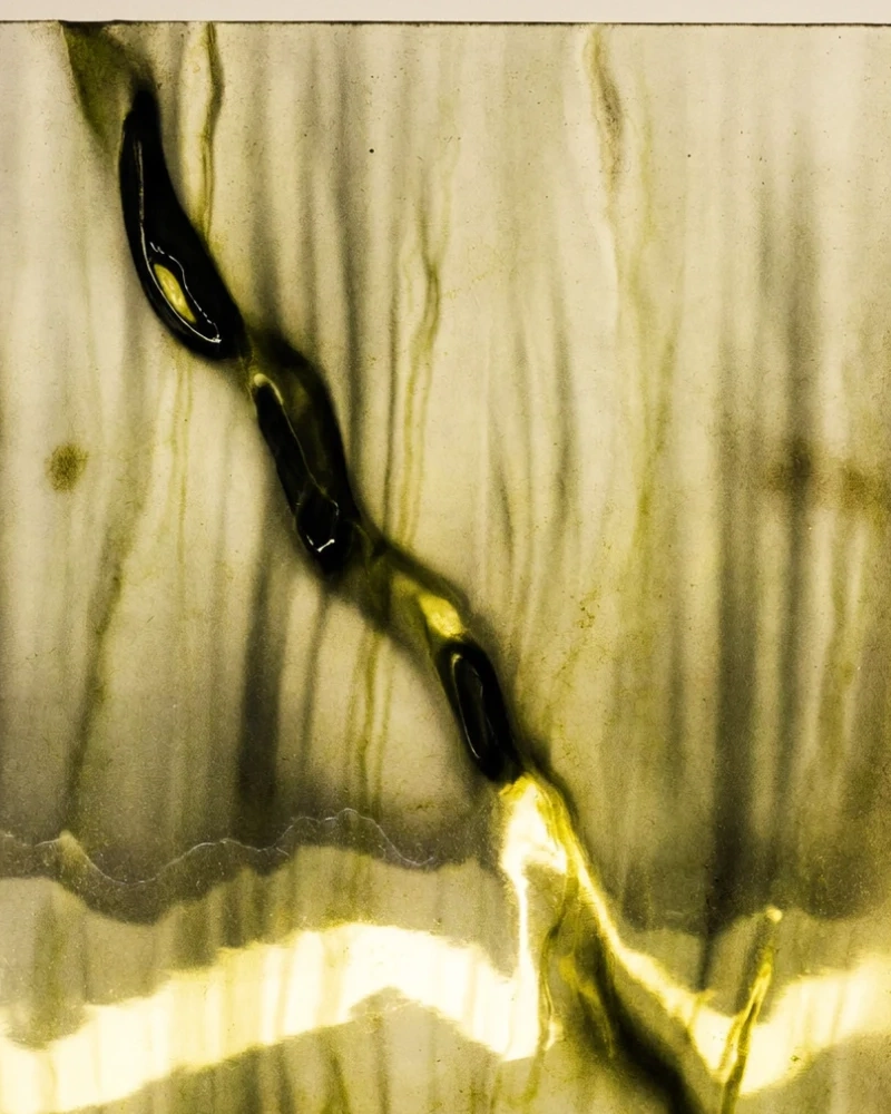 Abstract material study: a cast glass panel veined in olive green, lit from behind, AI concept work