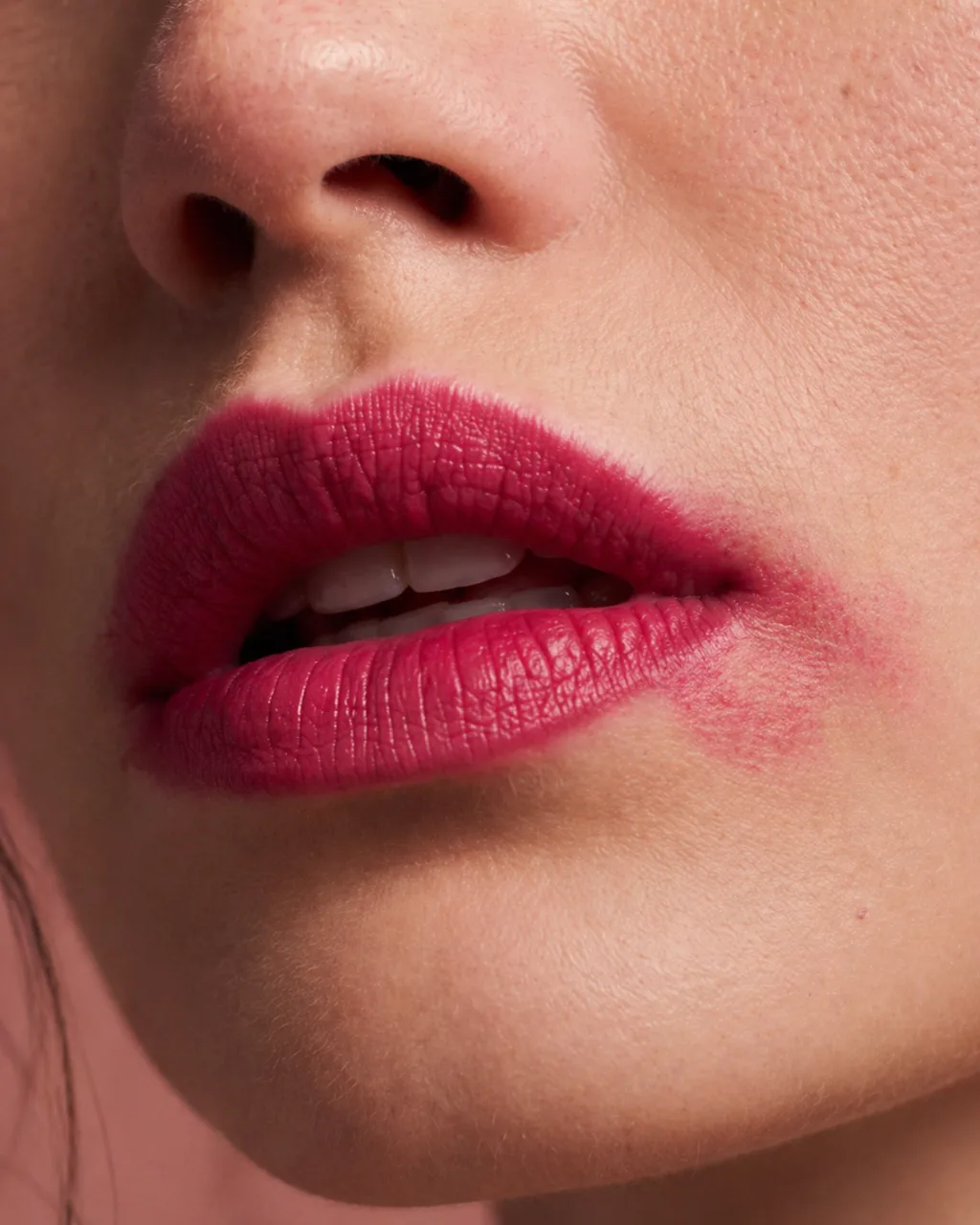 MUSE lipstick on the lips in macro, a magenta shade softly smudged at one corner
