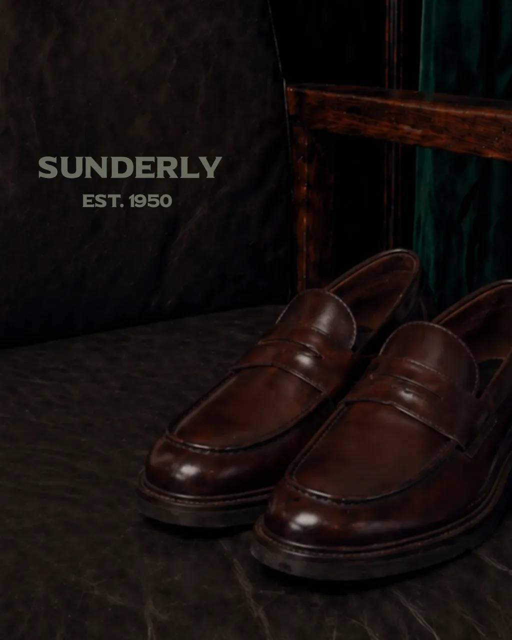 SUNDERLY key visual: brown penny loafers on a leather chair by dark wood and velvet, with the lettering, AI concept work