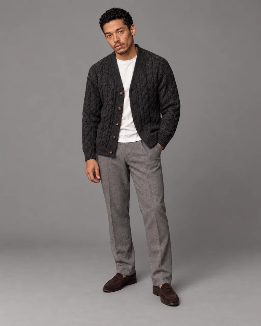 Sunderly look 6, charcoal cable cardigan and grey flannel trousers: full length on a plain grey ground, AI concept work